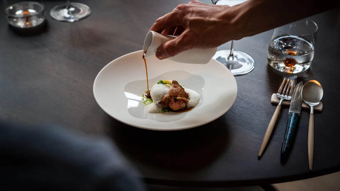 Jus being poured over a dish at the table